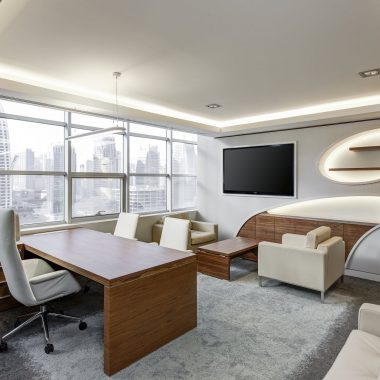 gray office rolling chair near brown wooden desk in front of flat screen tv on white painted wall