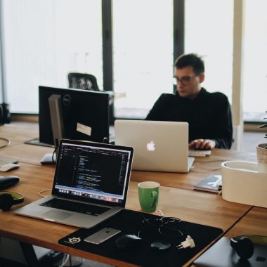 man in black shirt sits behind desk with computers