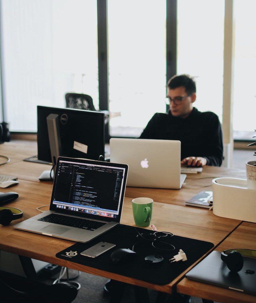 man in black shirt sits behind desk with computers