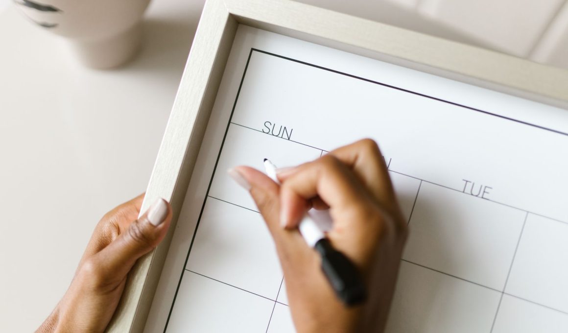 Iemand plant werkdagen op een wandkalender om twee banen te combineren