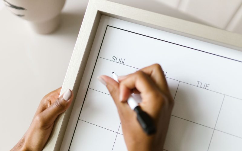 Iemand plant werkdagen op een wandkalender om twee banen te combineren